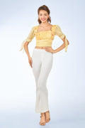 Woman wearing a yellow top and white pants on a light blue background from vandamod designer fashion singapore