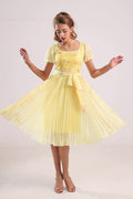 Woman wearing a yellow floral chiffon pleated dress with a white background from vandamod designer fashion singapore