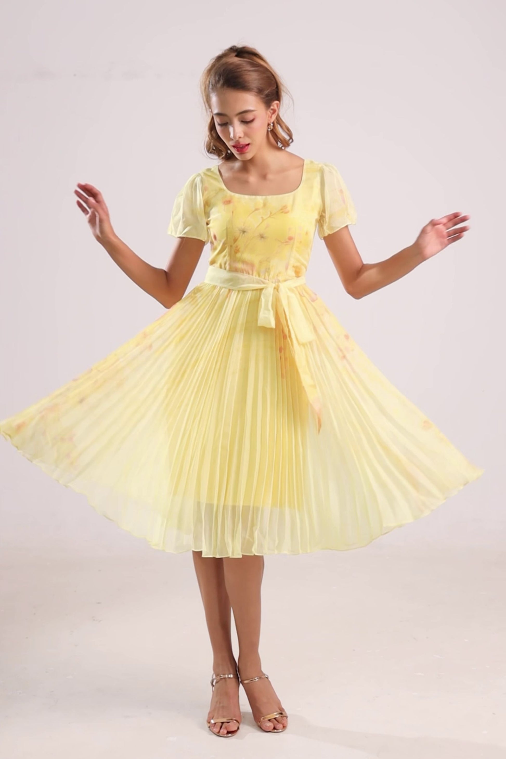 Woman wearing a yellow floral chiffon pleated dress with a white background from vandamod designer fashion singapore