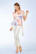 Woman wearing a colorful top and white pants on a light gray background from vanda singapore fashion